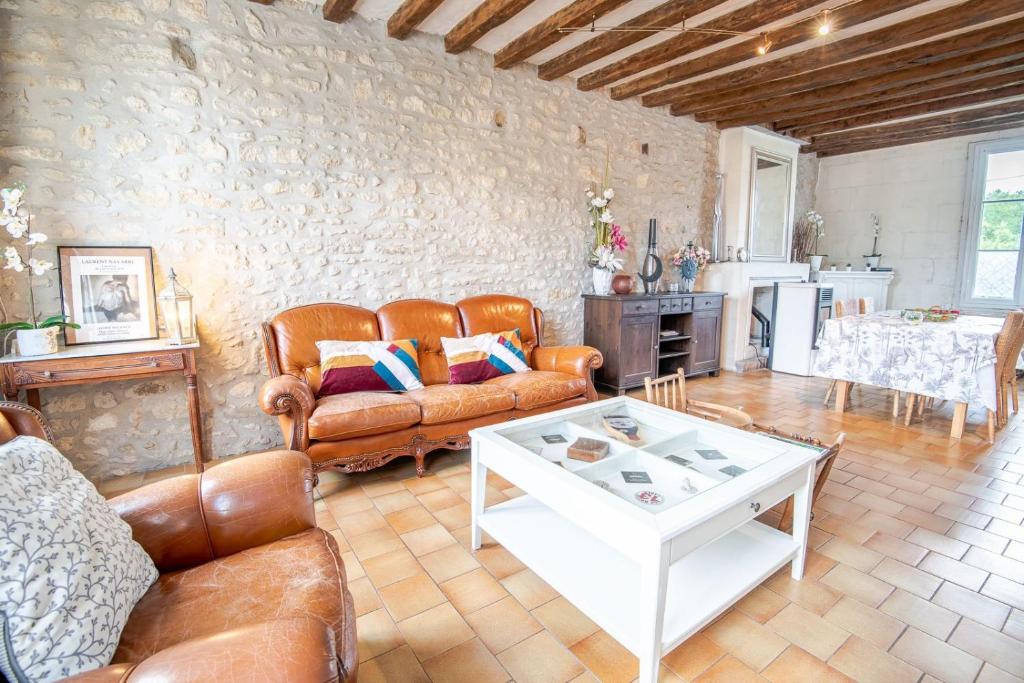 a living room with leather furniture and a white table at La Maison du Bonheur - Francueil in Francueil