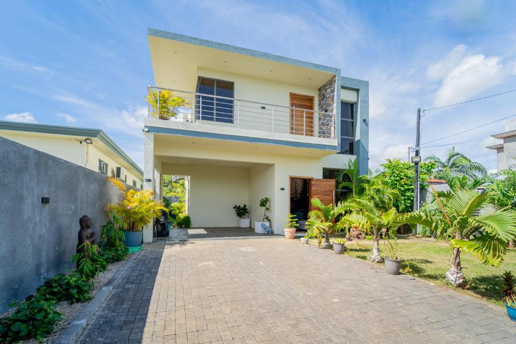 a house with a balcony and a brick driveway at Keenoo Villa - An elegant villa in a calm area in Pamplemousses Village