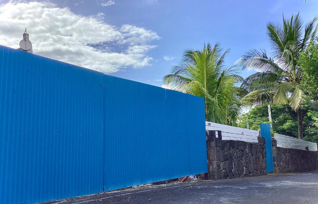 Una pared azul con palmeras detrás. en Original Villa en Trou dʼ Eau Douce