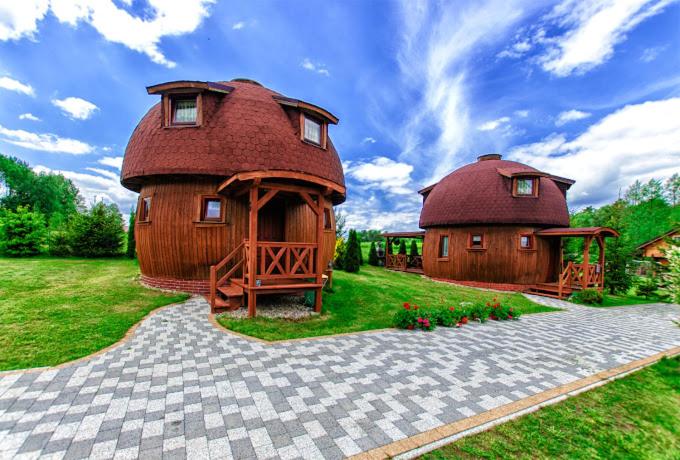 ein großes Haus mit einem runden Dach auf einem Feld in der Unterkunft Oaza Ławki in Ryn
