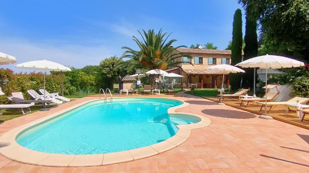uma piscina com cadeiras e guarda-sóis e uma casa em Villa Daya by BarbarHouse em Carignano