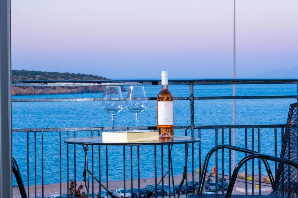 a bottle of wine and two glasses on a table on a balcony at Filia Home in Agios Nikolaos