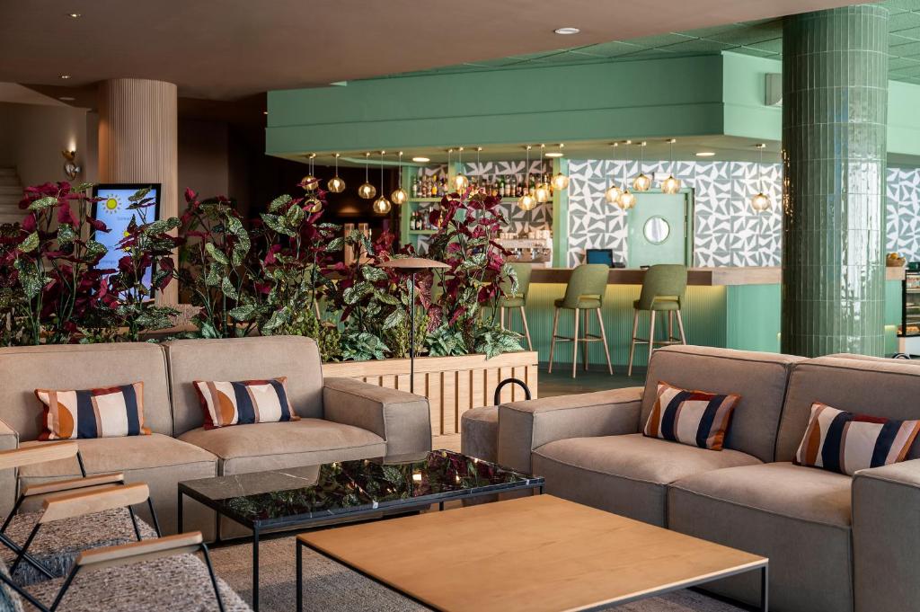 a lobby with couches and a bar with plants at Hesperia Barcelona Sant Just in Sant Just Desvern