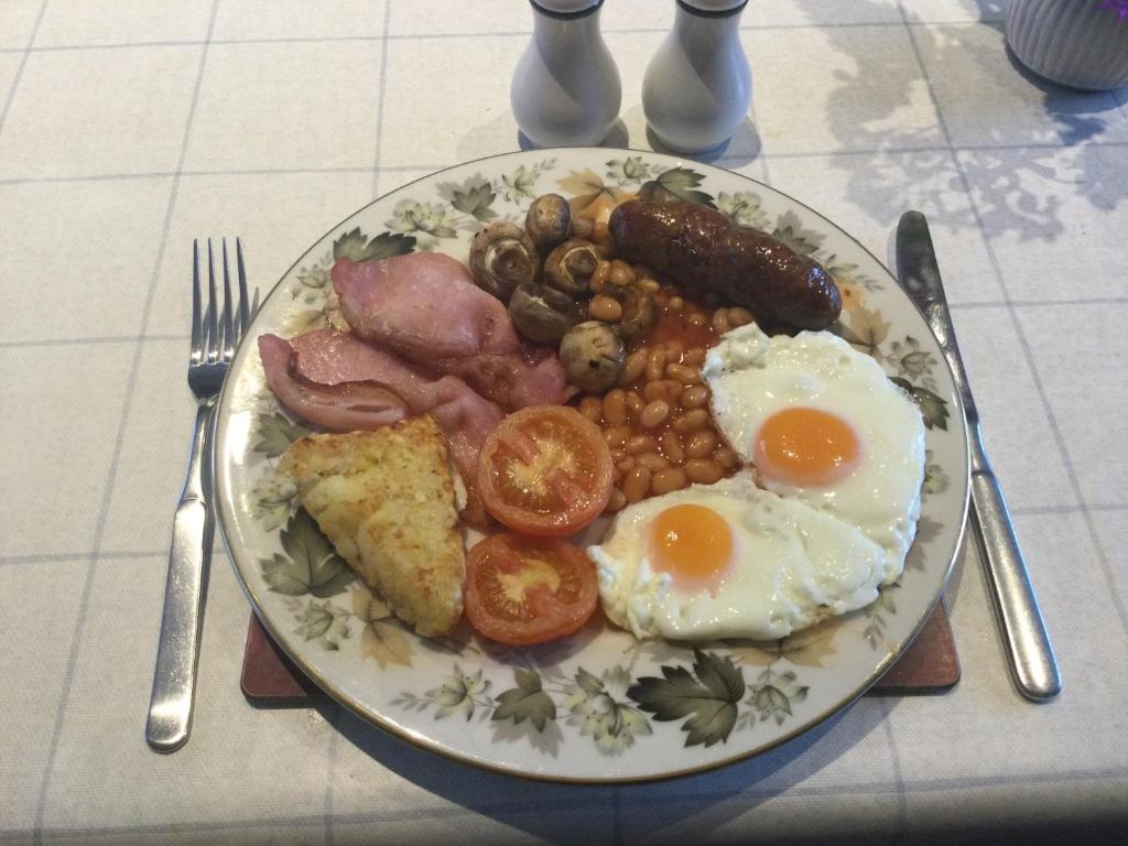 a plate of breakfast food with eggs sausage and beans at STACK YARD COTTAGE. in Cambridge