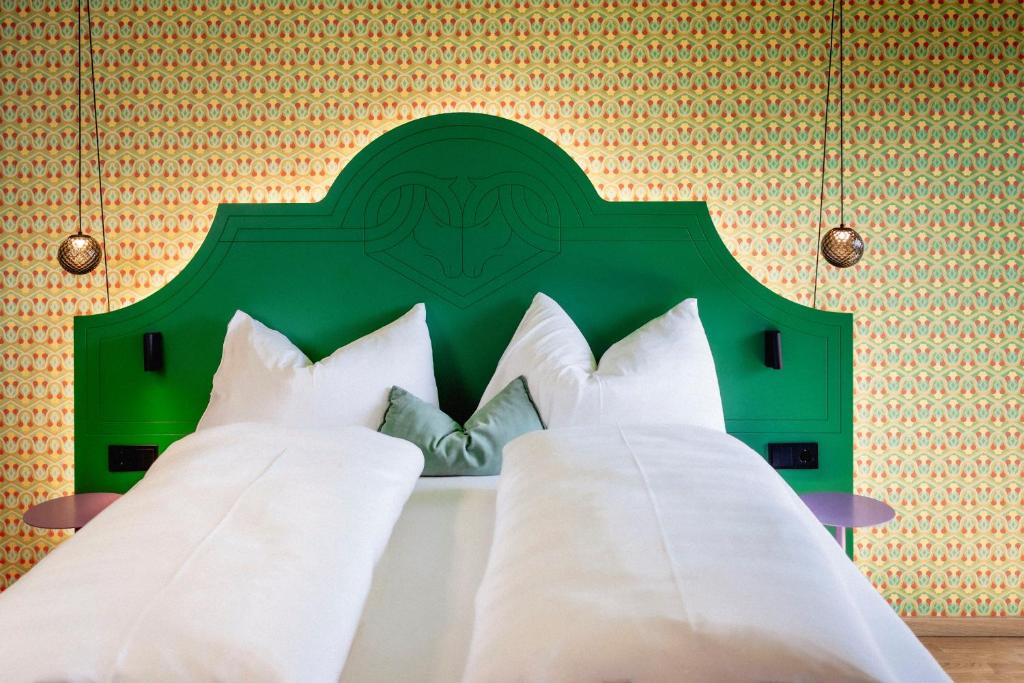 a bed with a green headboard and white pillows at Schwarzes Rössl in St. Wolfgang