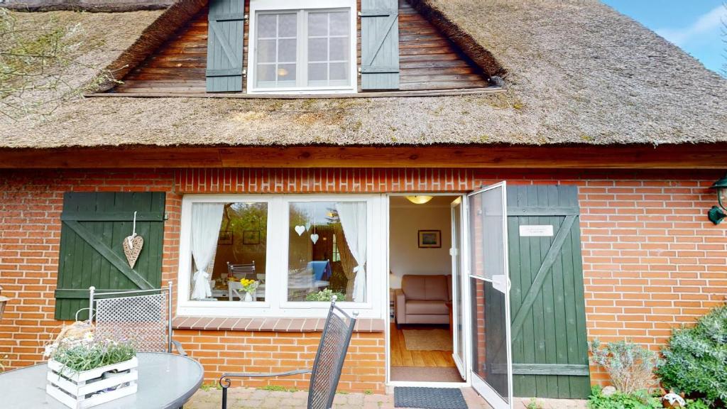a red brick house with green doors and a table at Gollendorf "Vier Pfoten" in Fehmarn
