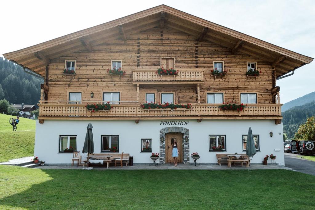 a large wooden building with tables and chairs in front at Der Pfindlhof in Leogang