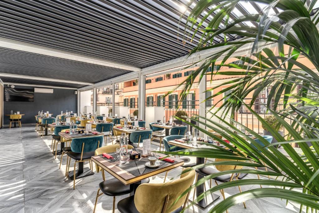 a restaurant with tables and chairs and a plant at CC Palace Hotel in Rome