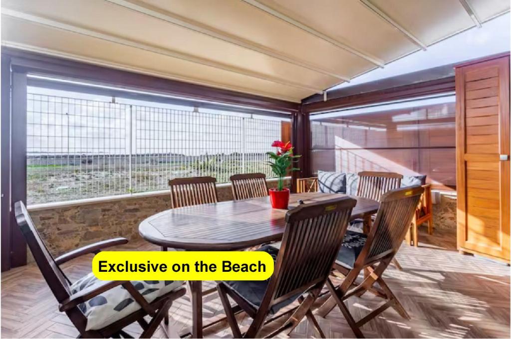 uma sala de jantar com uma mesa e cadeiras e uma janela em Appartamento Esclusivo sulla Spiaggia - 10 minuti dall'Aeroporto em Fiumicino
