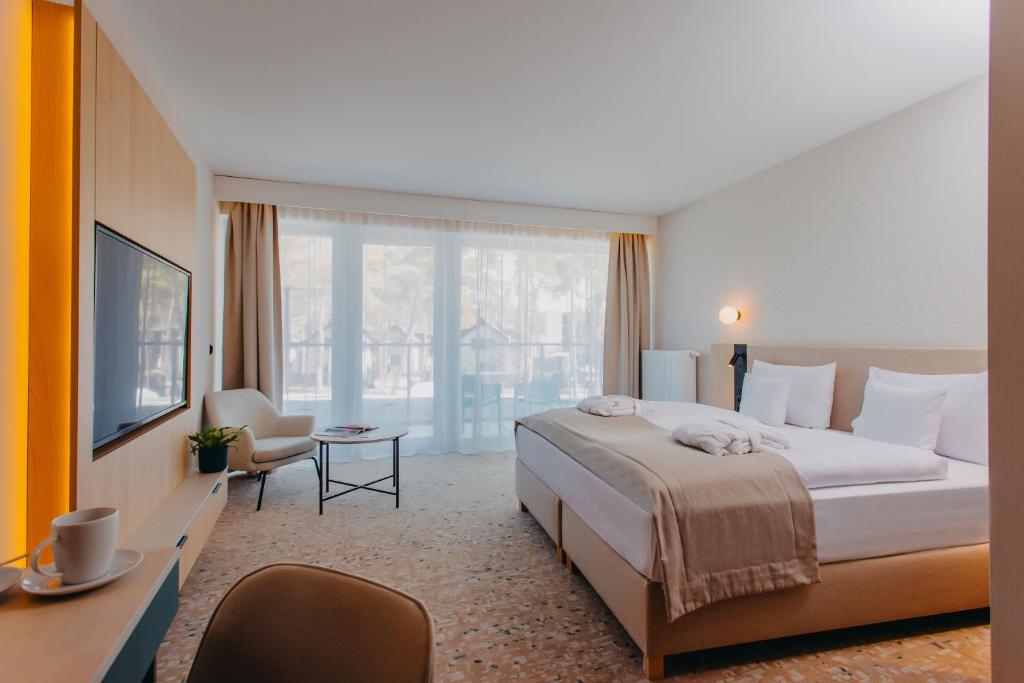 ポビエロボにあるHotel Linea Mareのベッドと大きな窓が備わるホテルルームです。