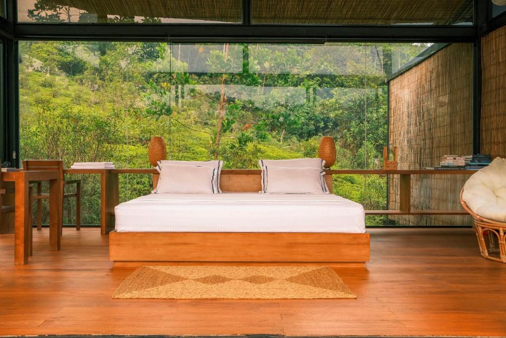 Bett in einem Zimmer mit einem großen Fenster in der Unterkunft Kurunduketiya Private Rainforest Resort in Kalawana