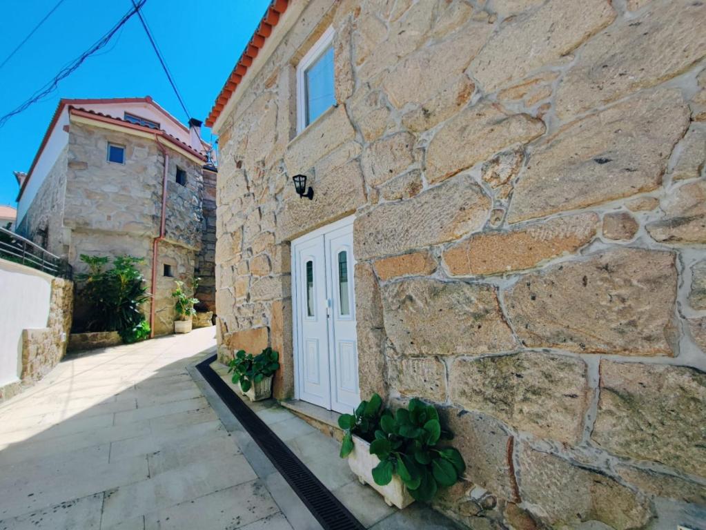 a stone building with a white door and some plants at Casinha do Sossego in Melgaço