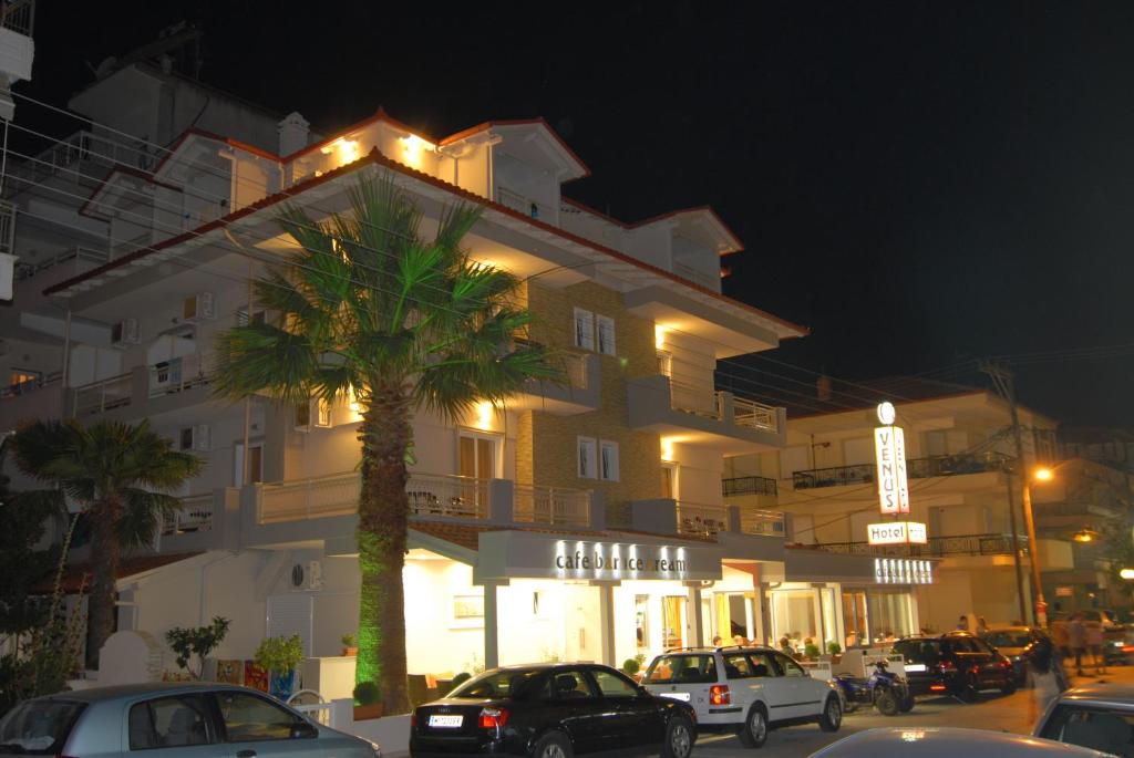 a building with cars parked in front of it at night at Hotel Venus in Paralia Katerinis