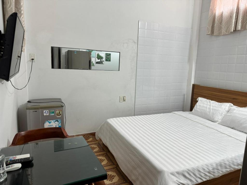 a small bedroom with a bed and a desk and a mirror at Hien CoCo Homestay Hoi An in Hoi An