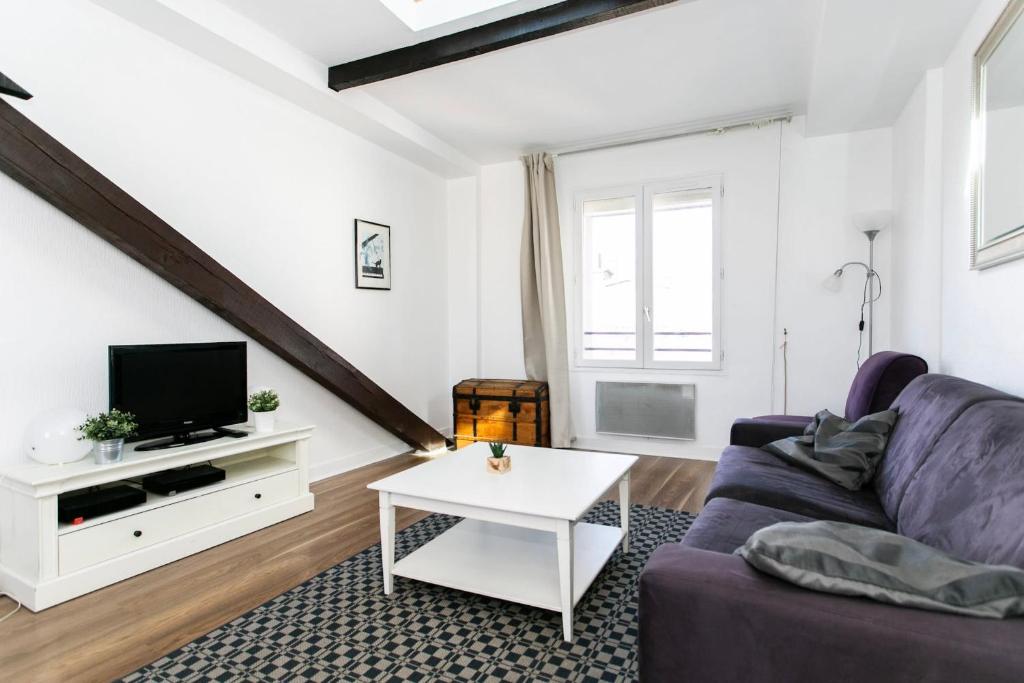 een woonkamer met een bank en een tv bij Arts et Métiers & Upper Marais - CityApartmentStay in Parijs