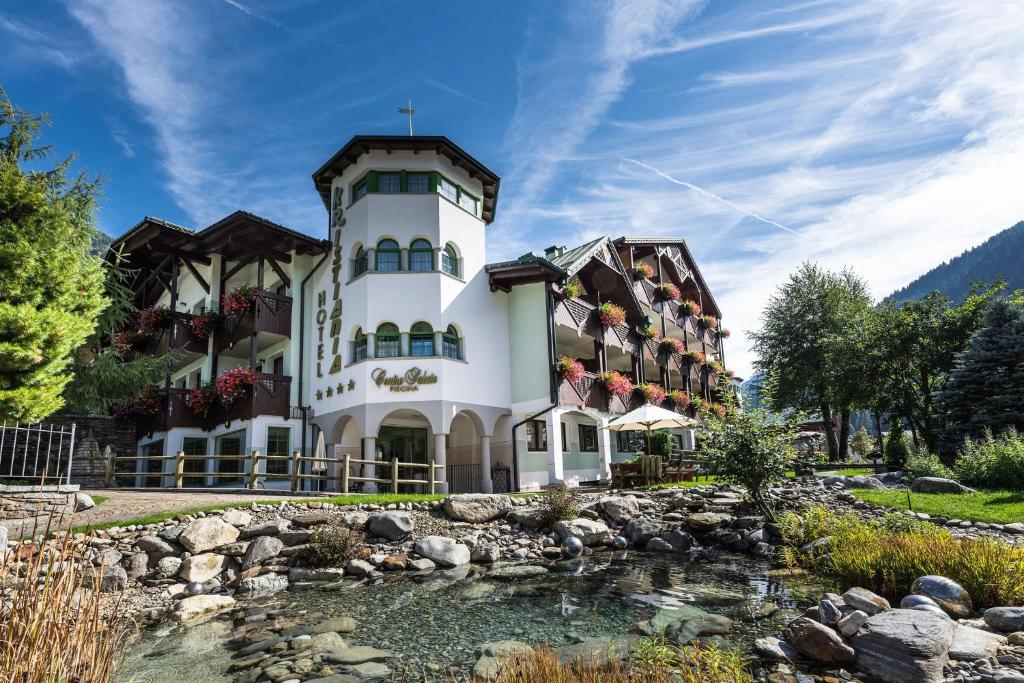 a building with a river in front of it at Kristiania Pure Nature Hotel & Spa in Cogolo