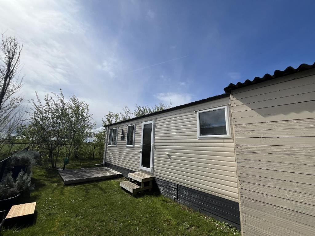 a tiny house with a porch next to a building at NV 1221 - Beach Resort Nieuwvliet Bad in Nieuwvliet