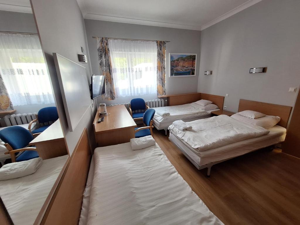 a room with two beds and a desk and chairs at Motel Comet in Przeźmierowo