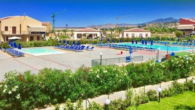- une grande piscine avec des chaises bleues dans un complexe dans l'établissement Casa Vacanze Isabella, à Campofelice di Roccella