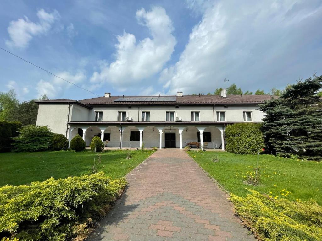 une grande maison blanche avec une allée en briques dans l'établissement Green House, à Wola Przypkowska