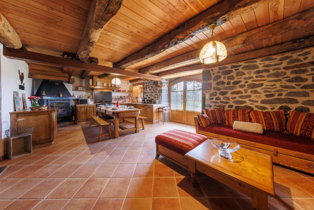 a living room with a couch and a stone wall at L'Anglardoise - Maison pour 10 voyageurs in Anglards-de-Salers
