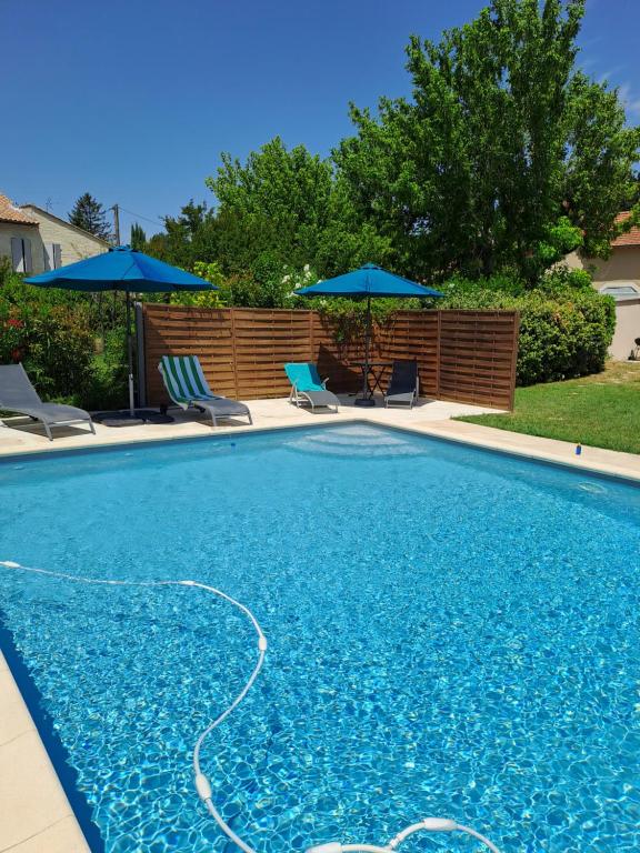 - une piscine avec 2 chaises longues et des parasols dans l'établissement LA LEZARDIERE CHEZ HUGUES, à Saint-Rémy-de-Provence