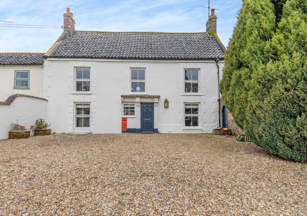 Una gran casa blanca con una puerta azul en The Old Post Office, en East Rudham