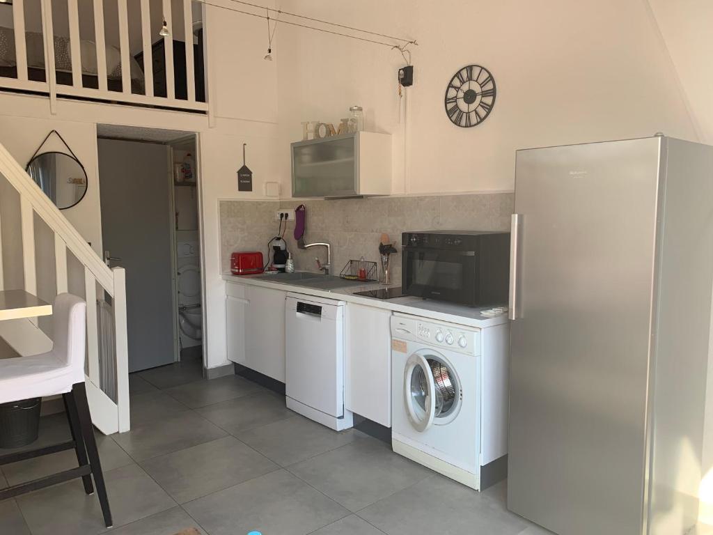 une cuisine avec un réfrigérateur et une machine à laver dans l'établissement La maison du bonheur 400 m de la plage de Richelieu, au Cap d'Agde