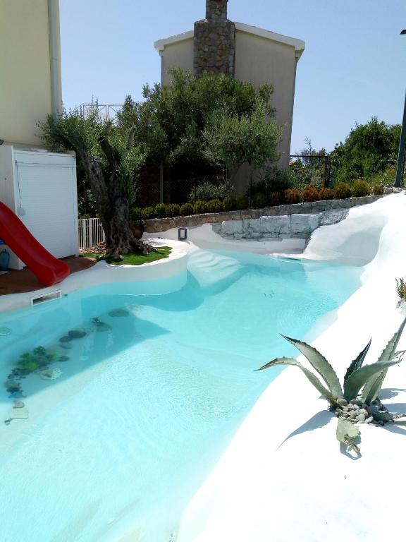 a resort pool with a slide and a palm tree at Suntime villa Laguna in Bigova