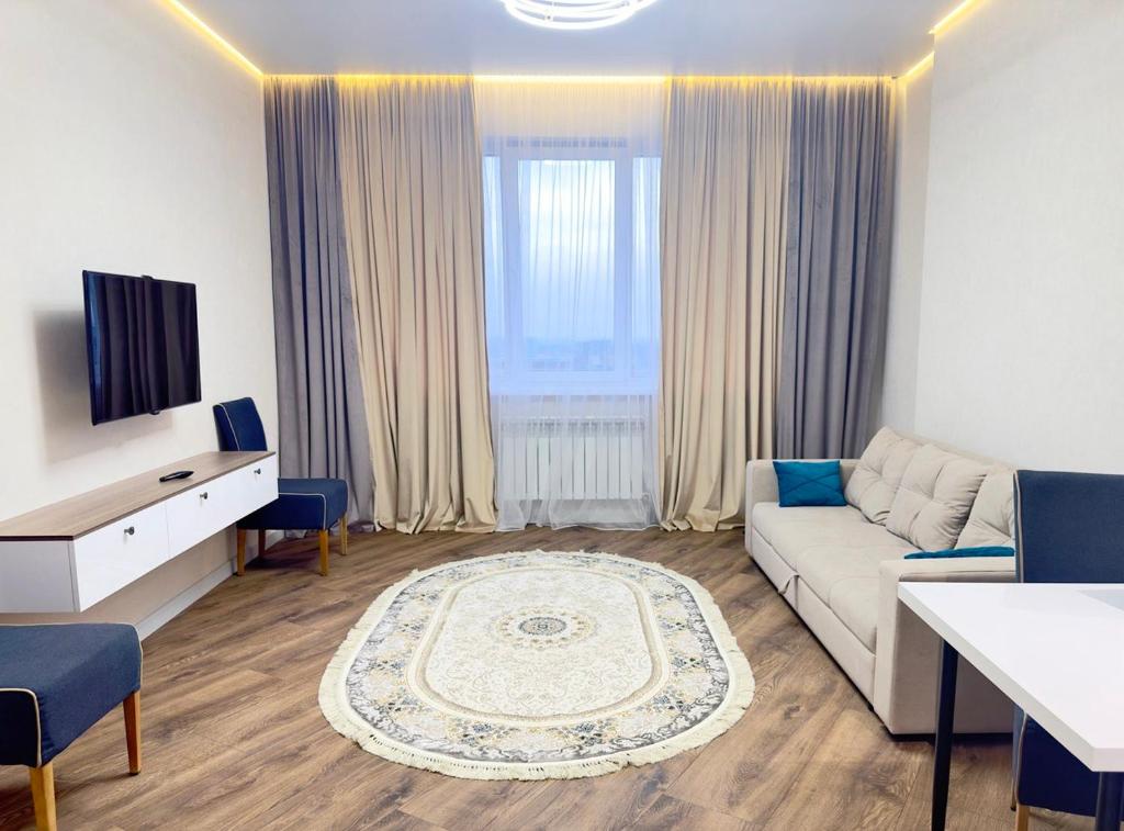 uma sala de estar com um sofá e uma televisão em Апартаменты в ЖК "AURUS" em Almaty