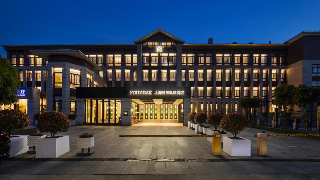 un bâtiment de bureau avec une façade éclairée la nuit dans l'établissement Fondney Hotel Shanghai Hongqiao, à Shanghai