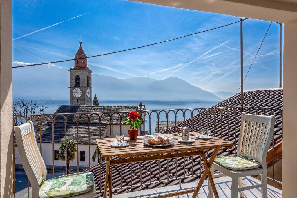 un tavolo e sedie su un balcone con torre dell'orologio. di Red View Apartment - Happy Rentals a Ronco sopra Ascona