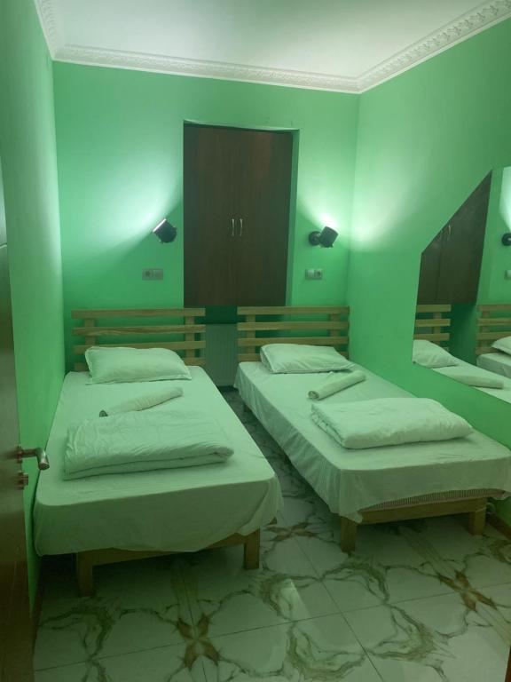um quarto verde com três camas e um espelho em Hostel Panda em Tbilisi