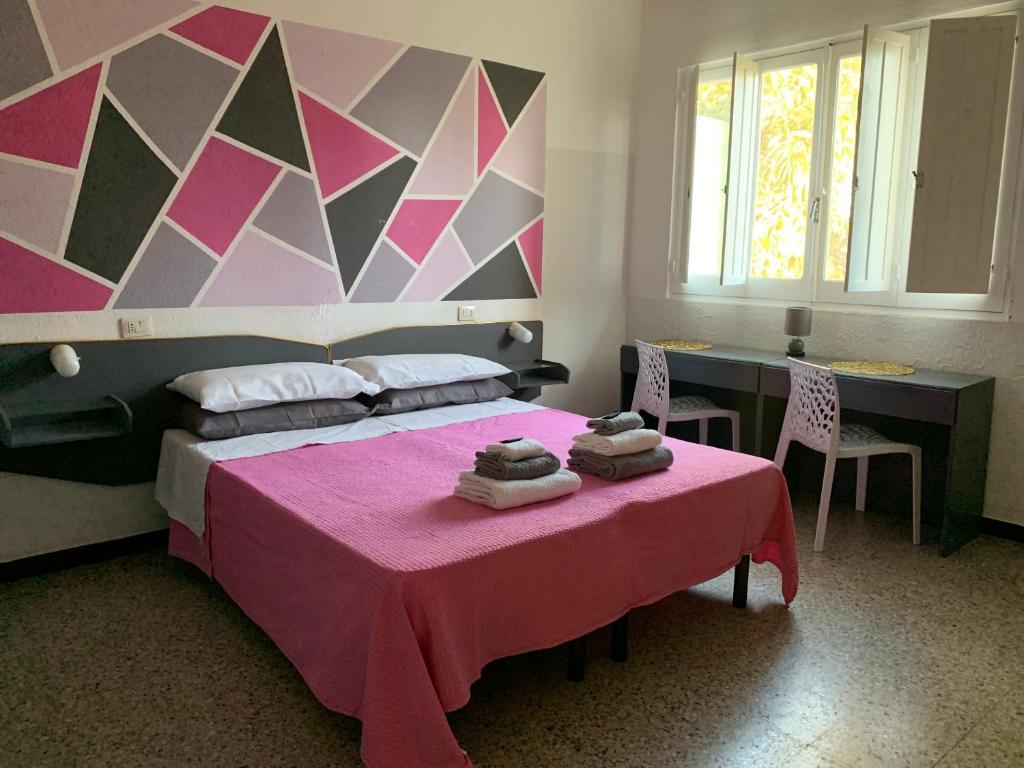 a bedroom with a pink bed with two towels on a table at Hotel Splendor in Tortolì