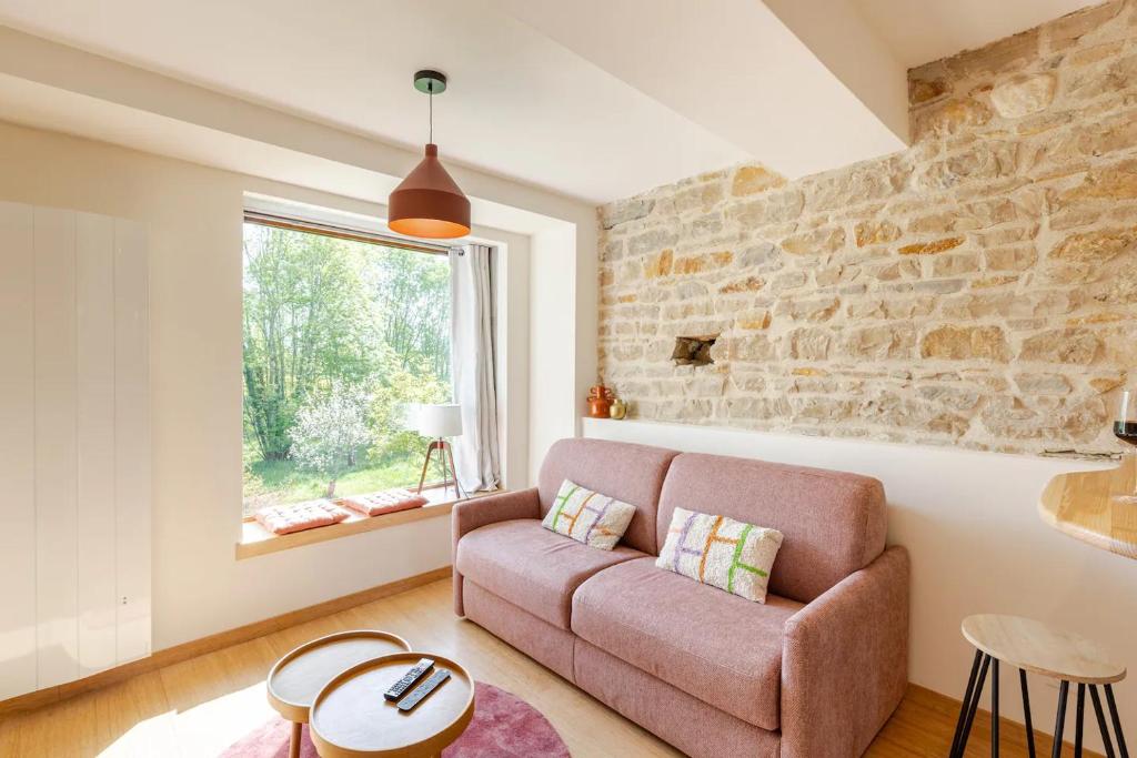 ein Wohnzimmer mit einem Sofa und einer Steinmauer in der Unterkunft Moulin du Buis - Bain nordique, charme et détente in Saint-Sorlin-en-Bugey