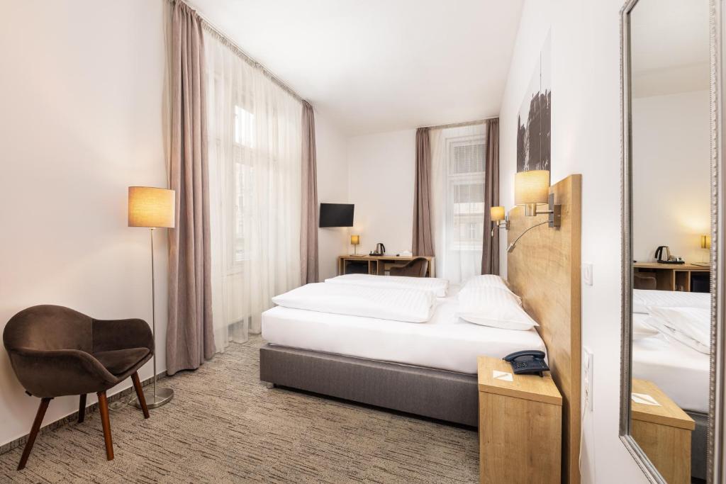 a bedroom with a bed and a chair and a mirror at City Hotel Ring in Budapest