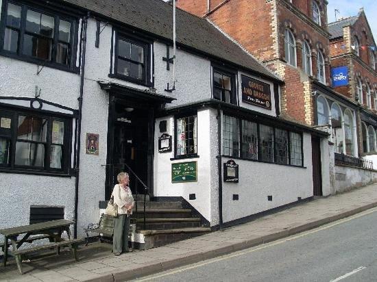 a woman standing outside of a white building at The George and Dragon Inn in Knighton