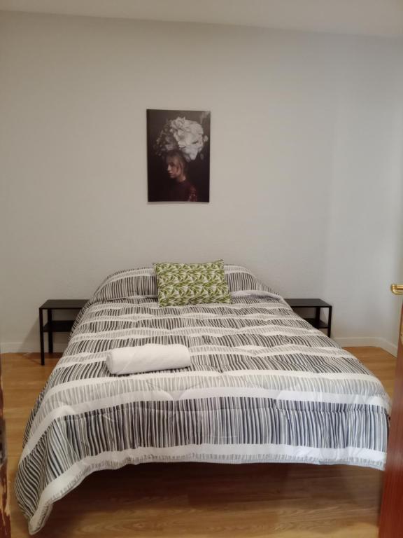 een bed met een gestreepte deken op een kamer bij Home P.C in Getafe