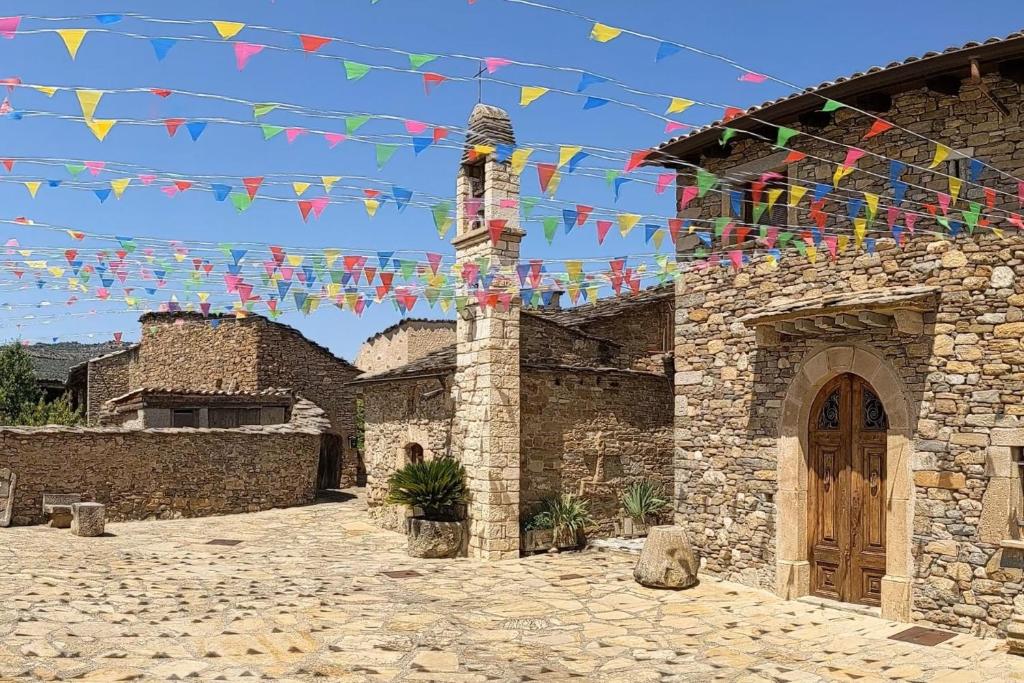 un bâtiment en pierre arborant des drapeaux colorés. dans l'établissement Casa Miret de Mur, à Vilamolat de Mur