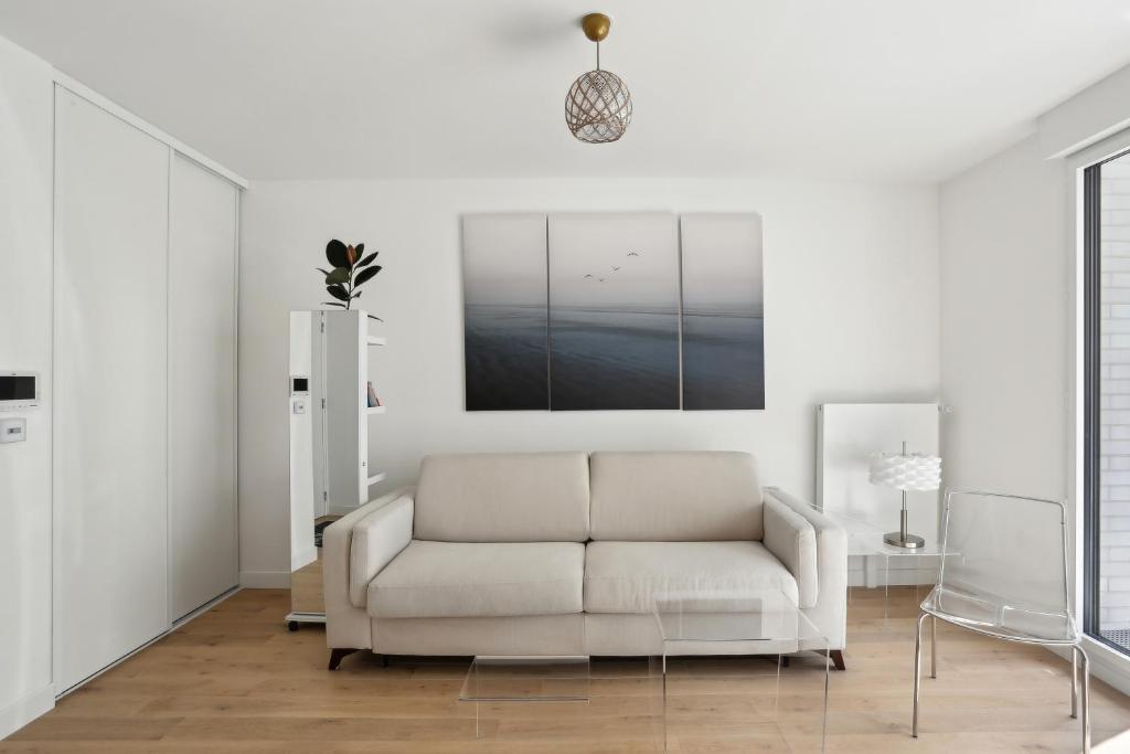 a white living room with a couch and a picture at Chic et minimaliste studio Batignolle/Montmartre by Weekome in Paris