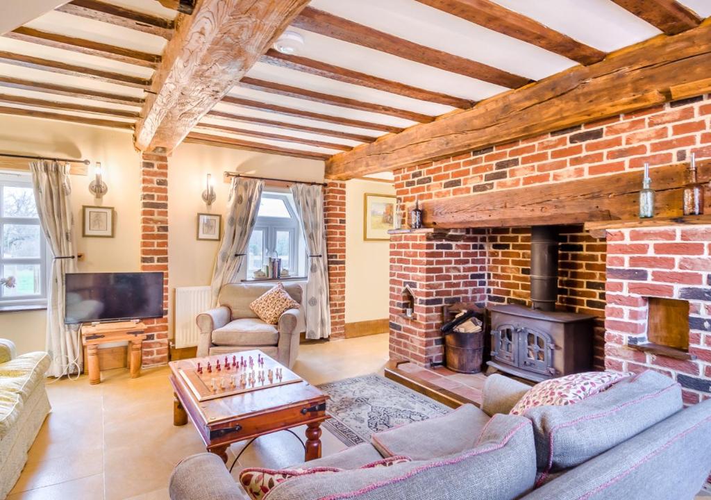 a living room with a brick wall and a fireplace at Orchard Cottage in East Dereham
