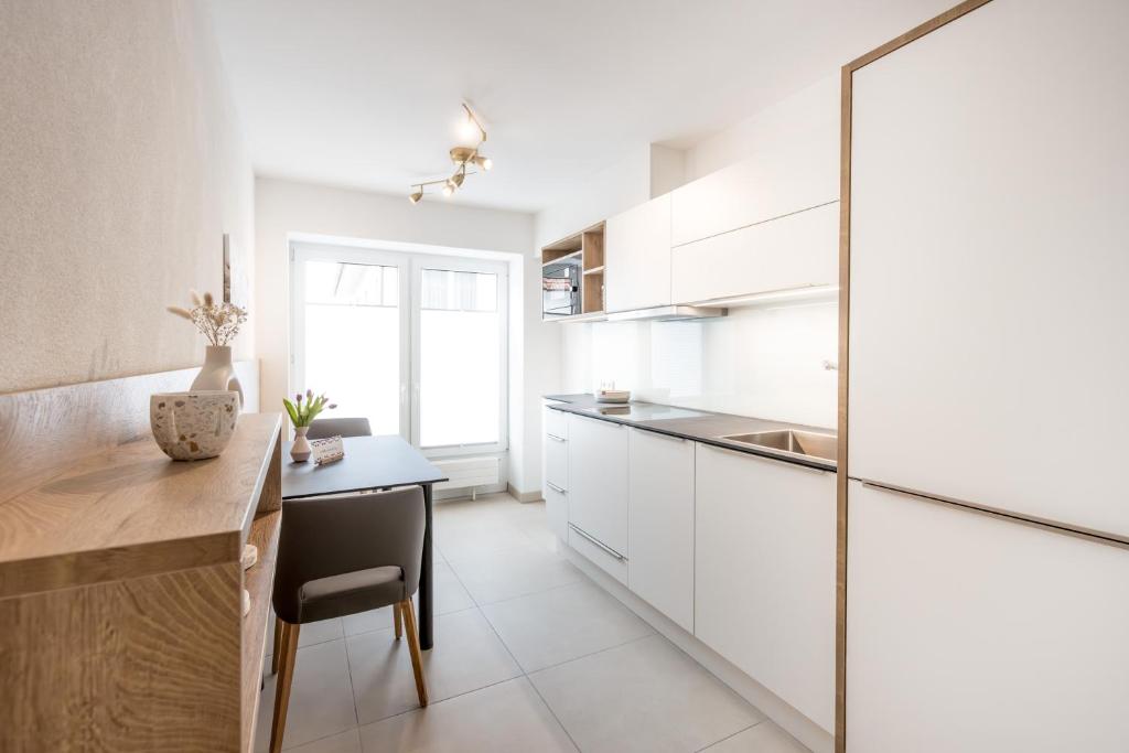 a kitchen with white cabinets and a table and a chair at das Blum in Hagnau
