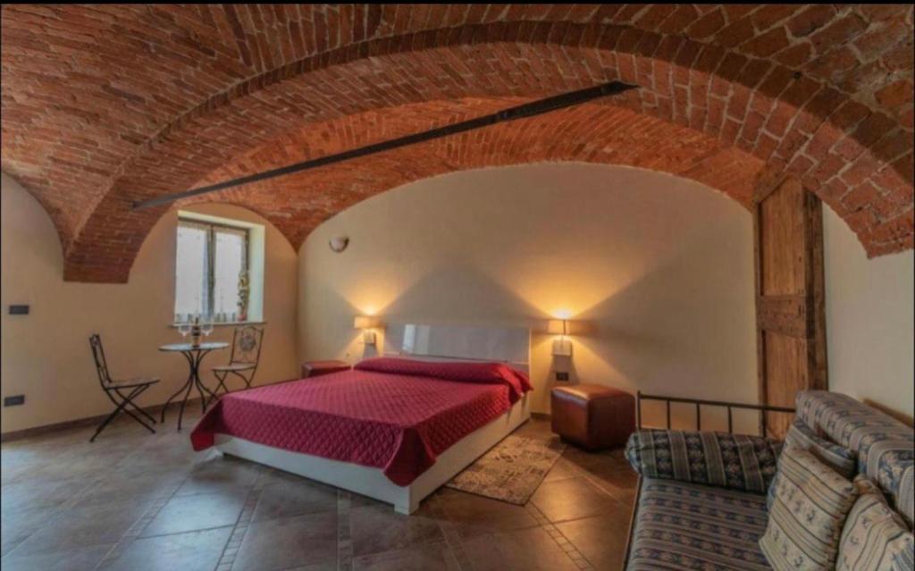 1 dormitorio con cama roja y pared de ladrillo en certe notti langhe, en Salmore