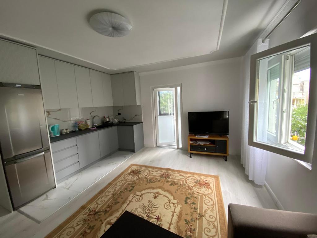 ein Wohnzimmer mit einer Küche und einem TV in der Unterkunft Apartament me qera 2+1 in Kukës