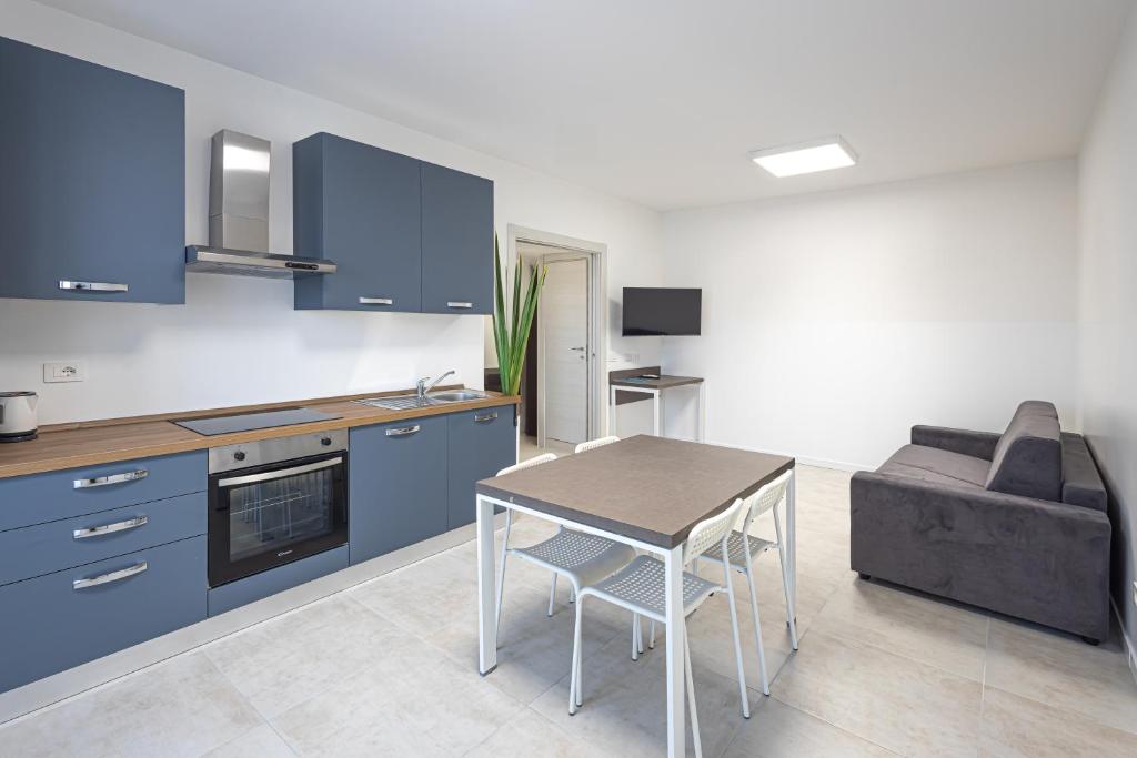 uma cozinha com armários azuis, uma mesa e um sofá em The Residence 2.0 em Galliate