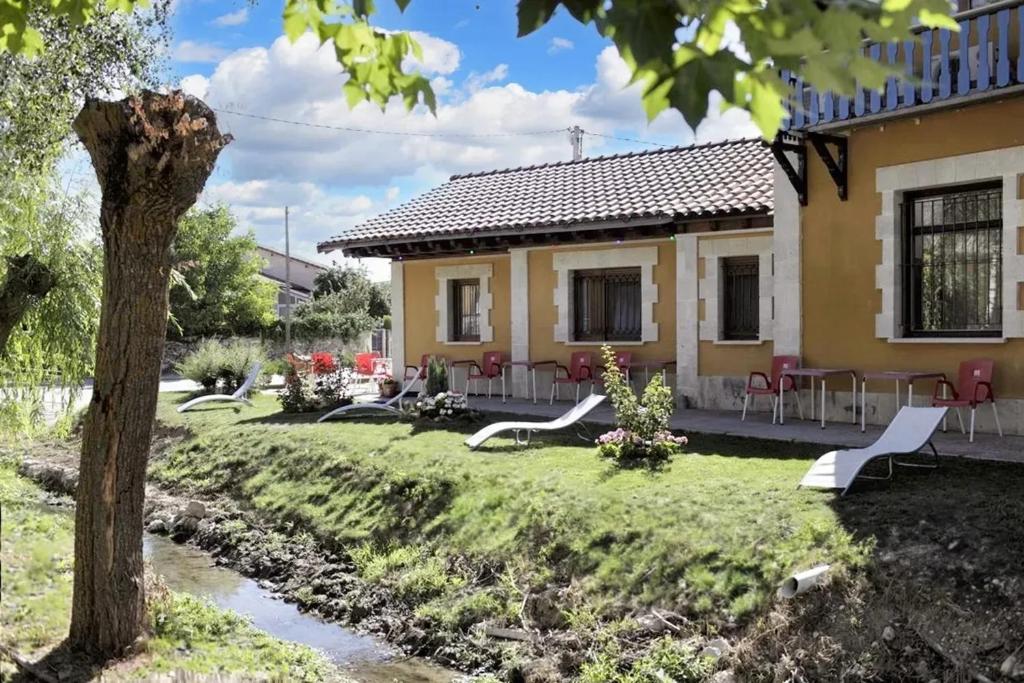 een huis met een tuin met stoelen en een kreek bij 6 bedrooms house with furnished garden and wifi at Cardenuela Riopico in Cardeñuela-Ríopico