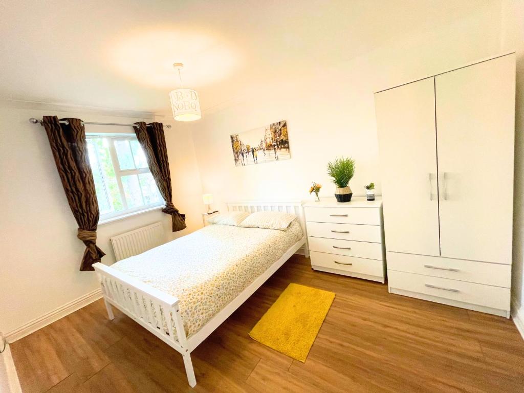 a white bedroom with a bed and a dresser at A Lovely Home Stay Near Greenwich in London