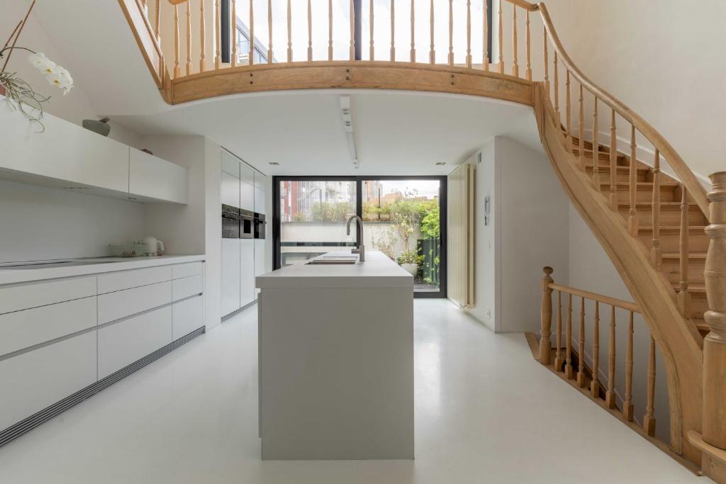 een keuken met witte kasten en een houten trap bij Spacious Belle Epoque House with free parking in Oostende