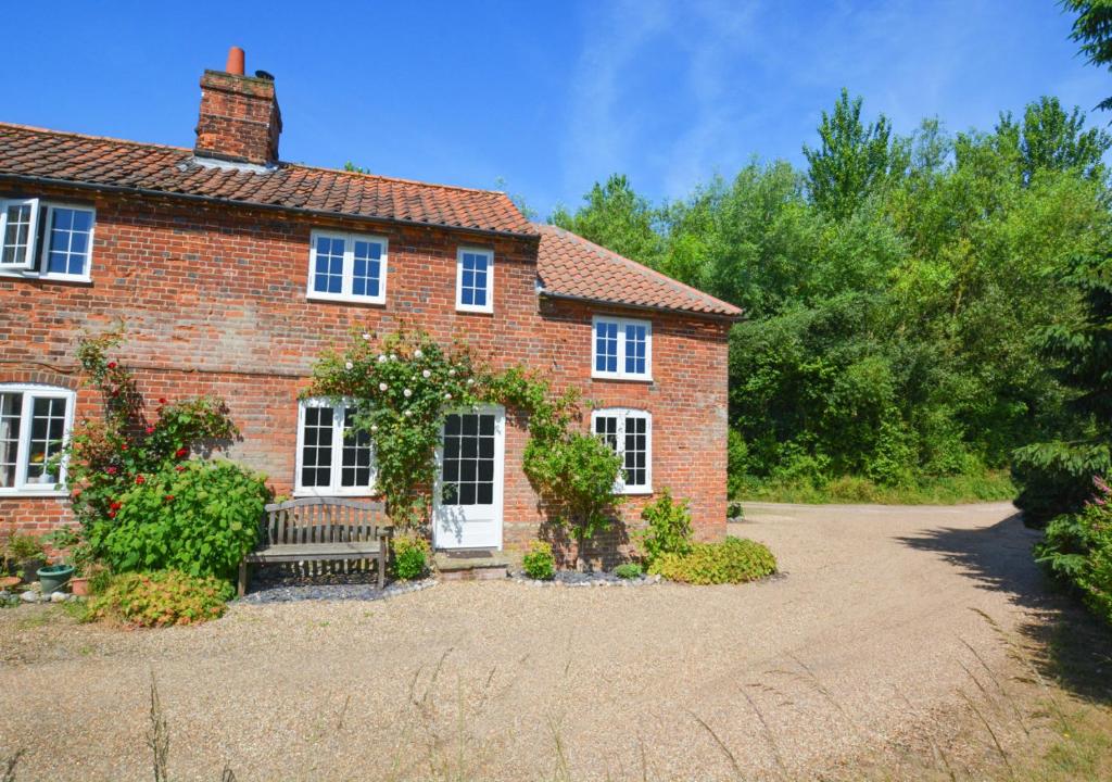 a brick house with a white door at Aurora Cottage in Little Barningham