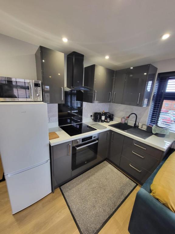 a kitchen with black cabinets and white appliances at Town Centre Modern 1 Bed self-contained Apartment in Newbury